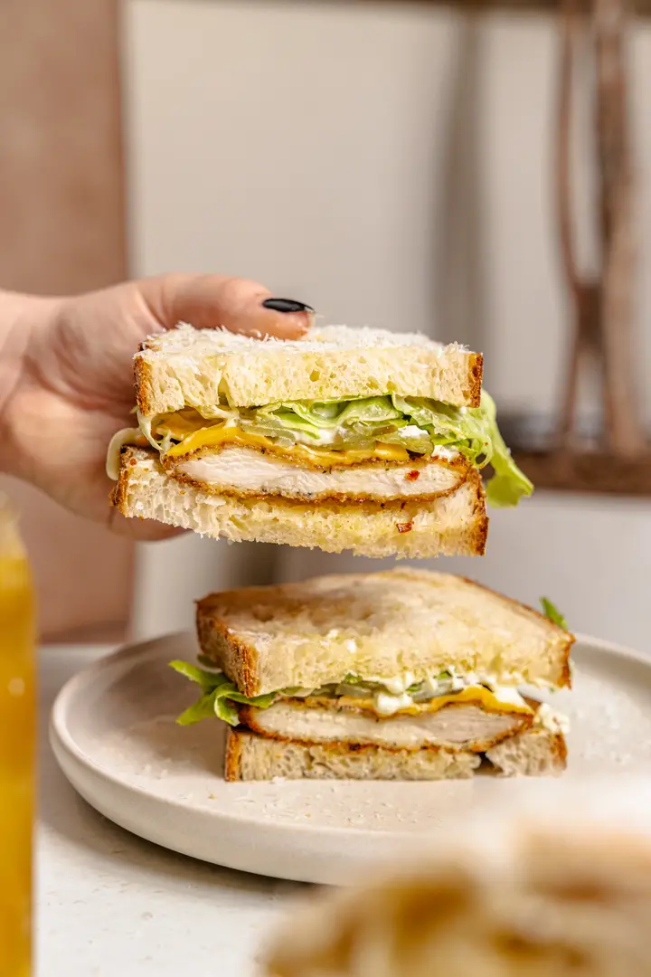 A crumbed chicken sandwich on thick-cut sourdough with lettuce, cheese and pickles